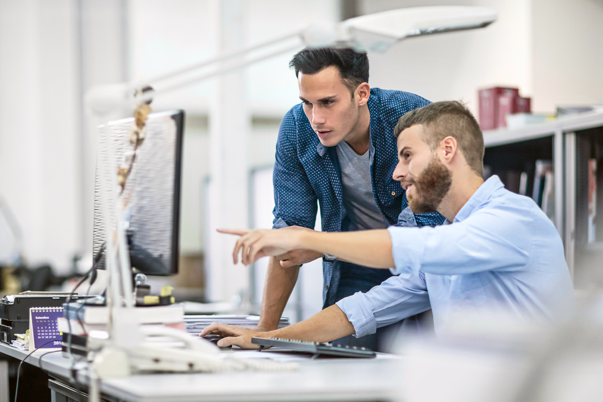 Two men discussing what is on a computer screen