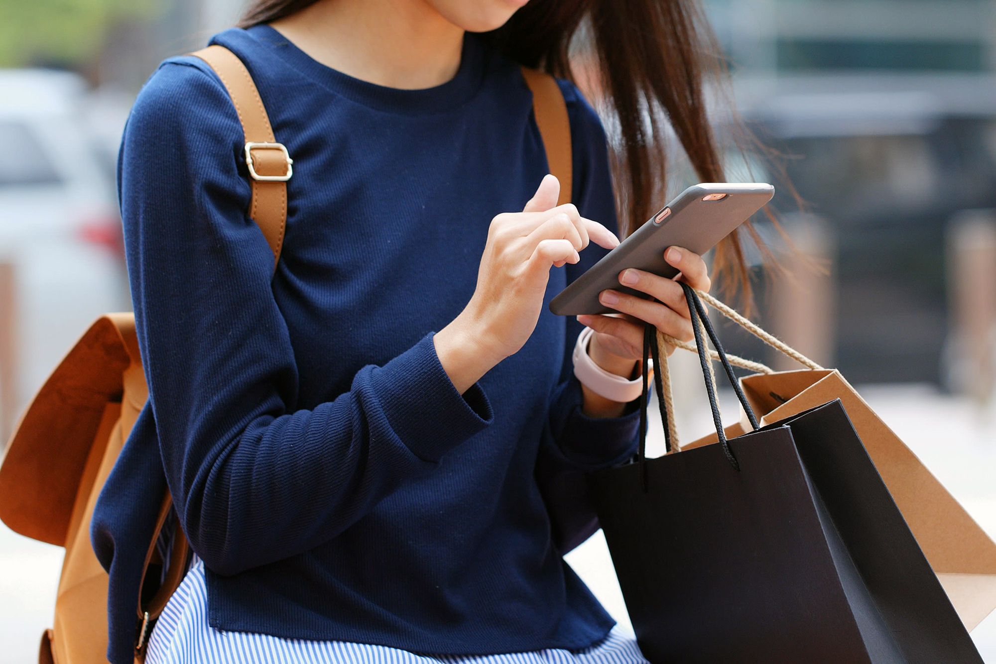 Women using mobile phone while holding shopping bags
